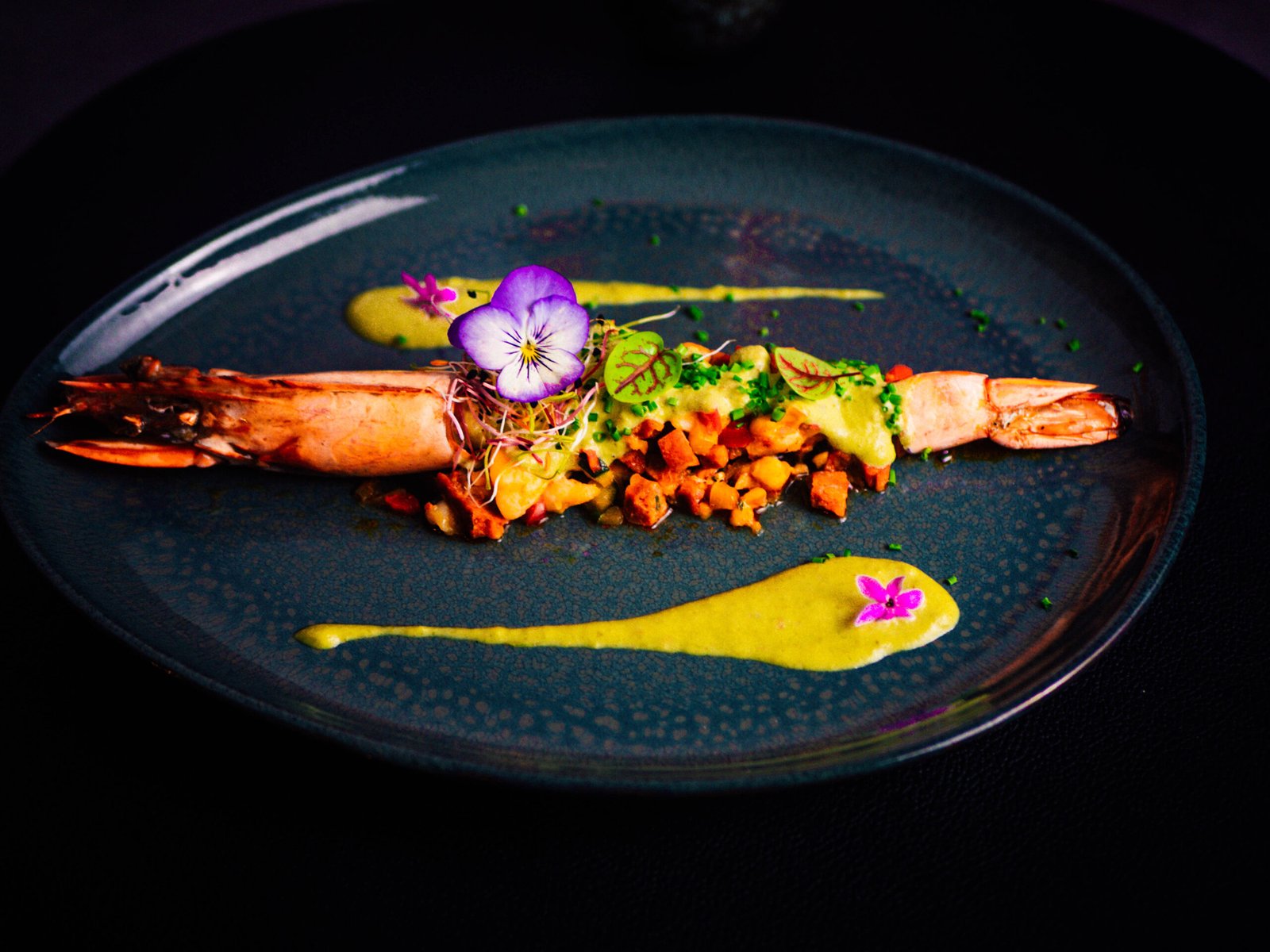 Assiette colorée dressée sur un fond sombre.